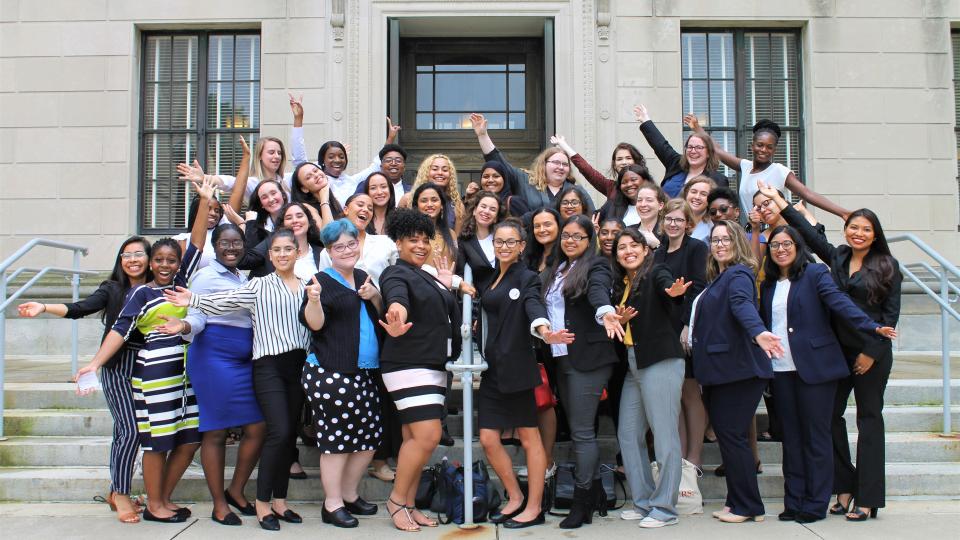 Large group of students standing on gray steps in front of Statehouse building