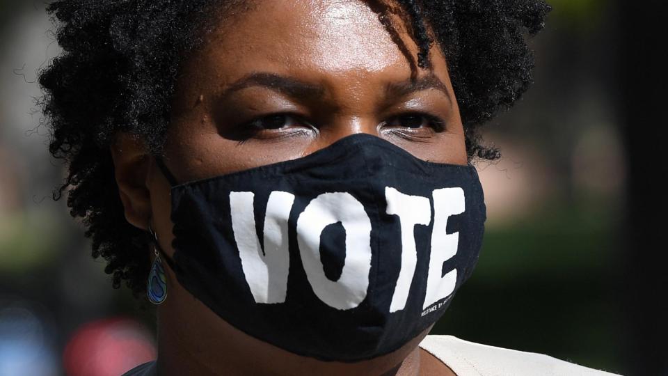 Stacey Abrams wears a face mask with the word Vote on it.