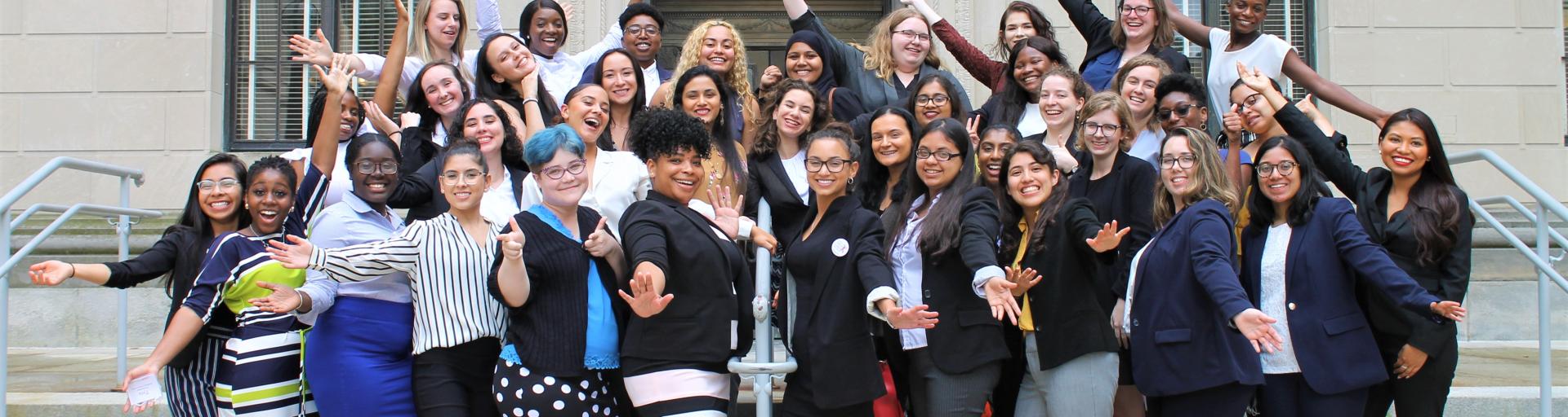 Large group of students standing on gray steps in front of Statehouse building