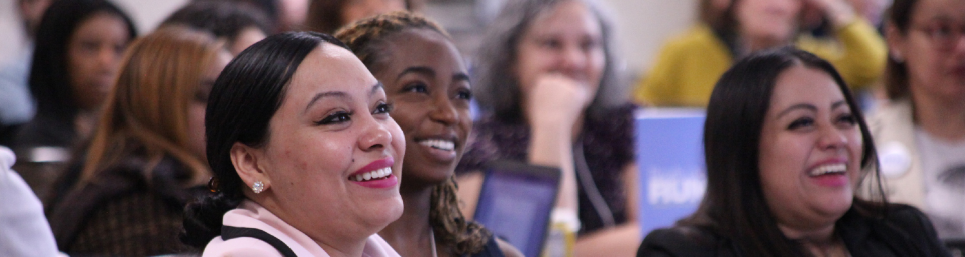 Shot of three women in a crowd, laughing 