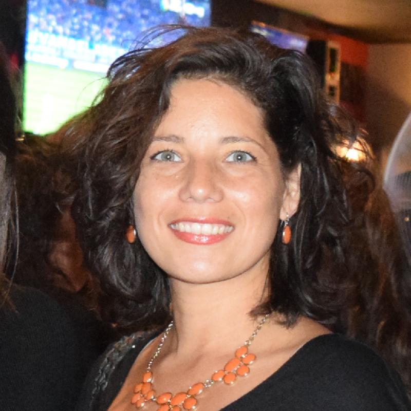 Head shot of Karol Ruiz wearing orange necklace and black shirt 