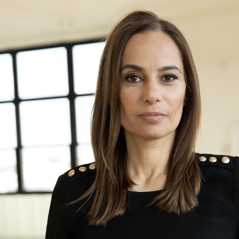 A photo of Julie Roginsky wearing a black sweater against a warm backdrop