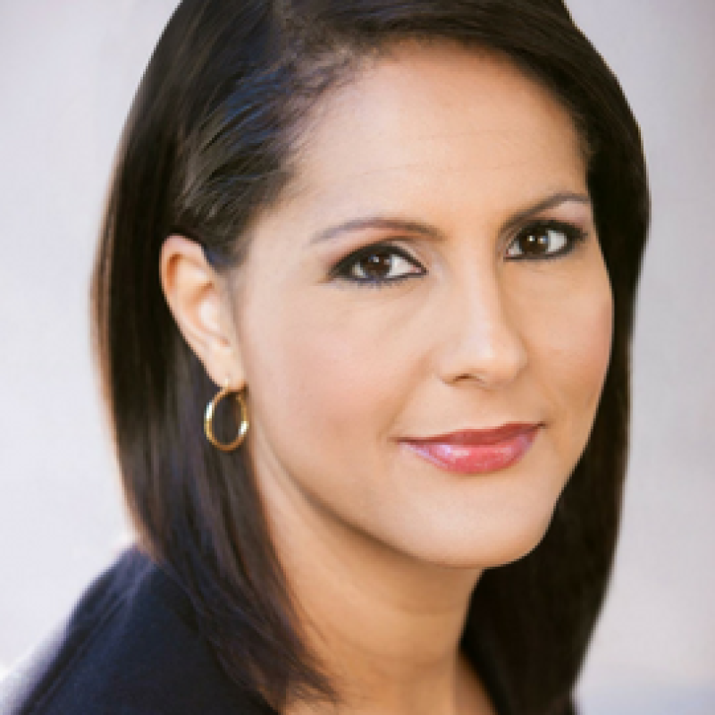 Close up shot of Karen Finney, she is smiling softly and looking over her shoulder at the camera