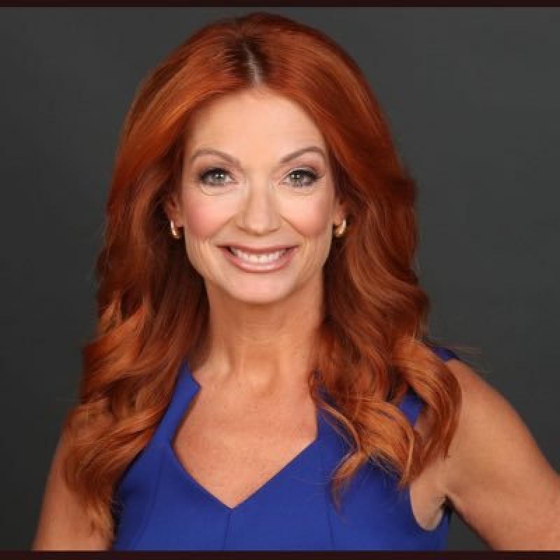 Jeanette Hoffman in a bright blue dress posed against a dark grey backdrop