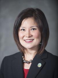 Susan Shin-Angulo smiles in black suit and red top